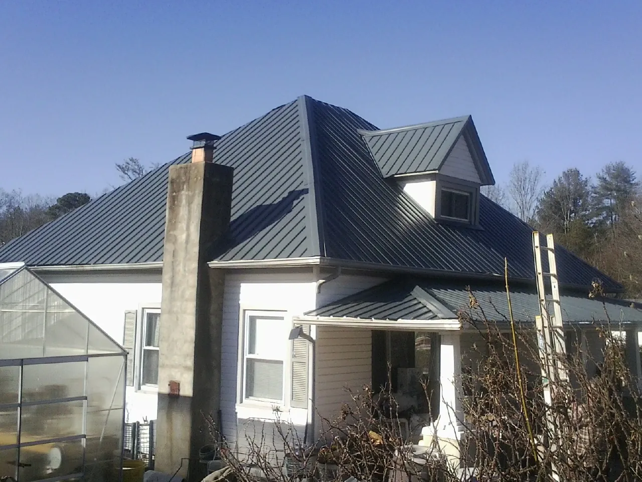 Dark blue standing seam metal roof on a white farmhouse with dormer — Slate & Tile Roof Repair by Roofing Brothers in Salley