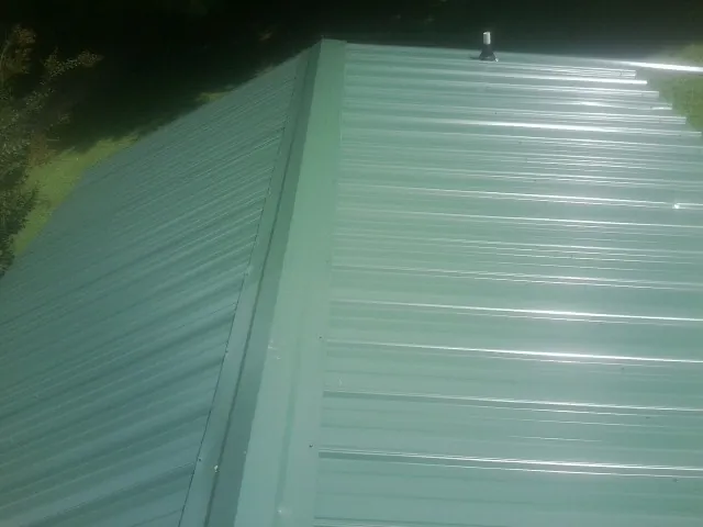 New green metal panels meeting at the ridge of a roof — Flat Roof Repair work by our crew in Salley