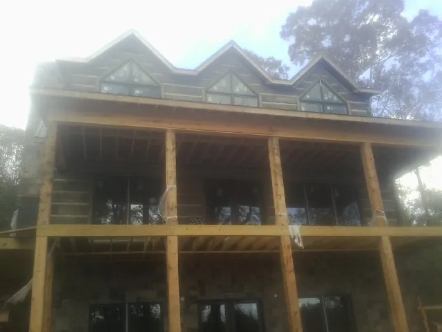 Dormers and porch framing on a large log home under construction — Roof Coating work by our crew in Salley