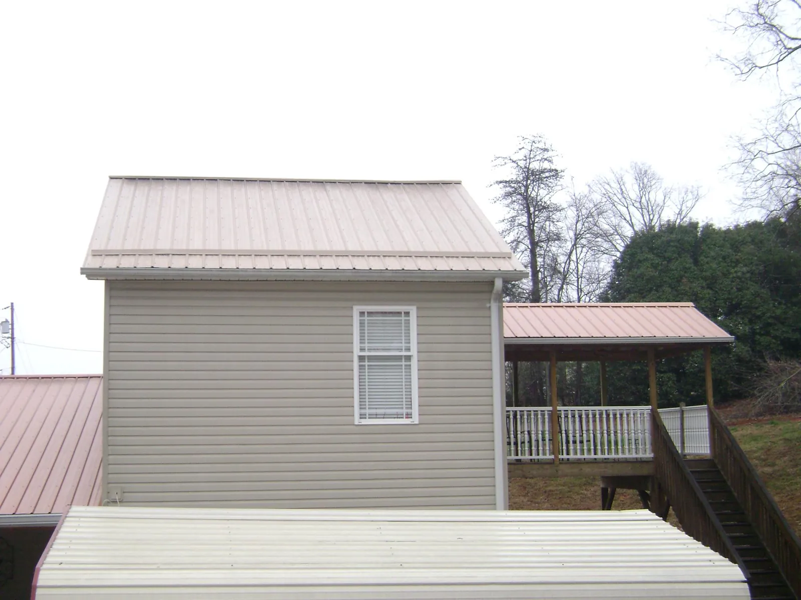 Tan metal roofs on a two story addition and attached porch, from a Roof Replacement job in Salley